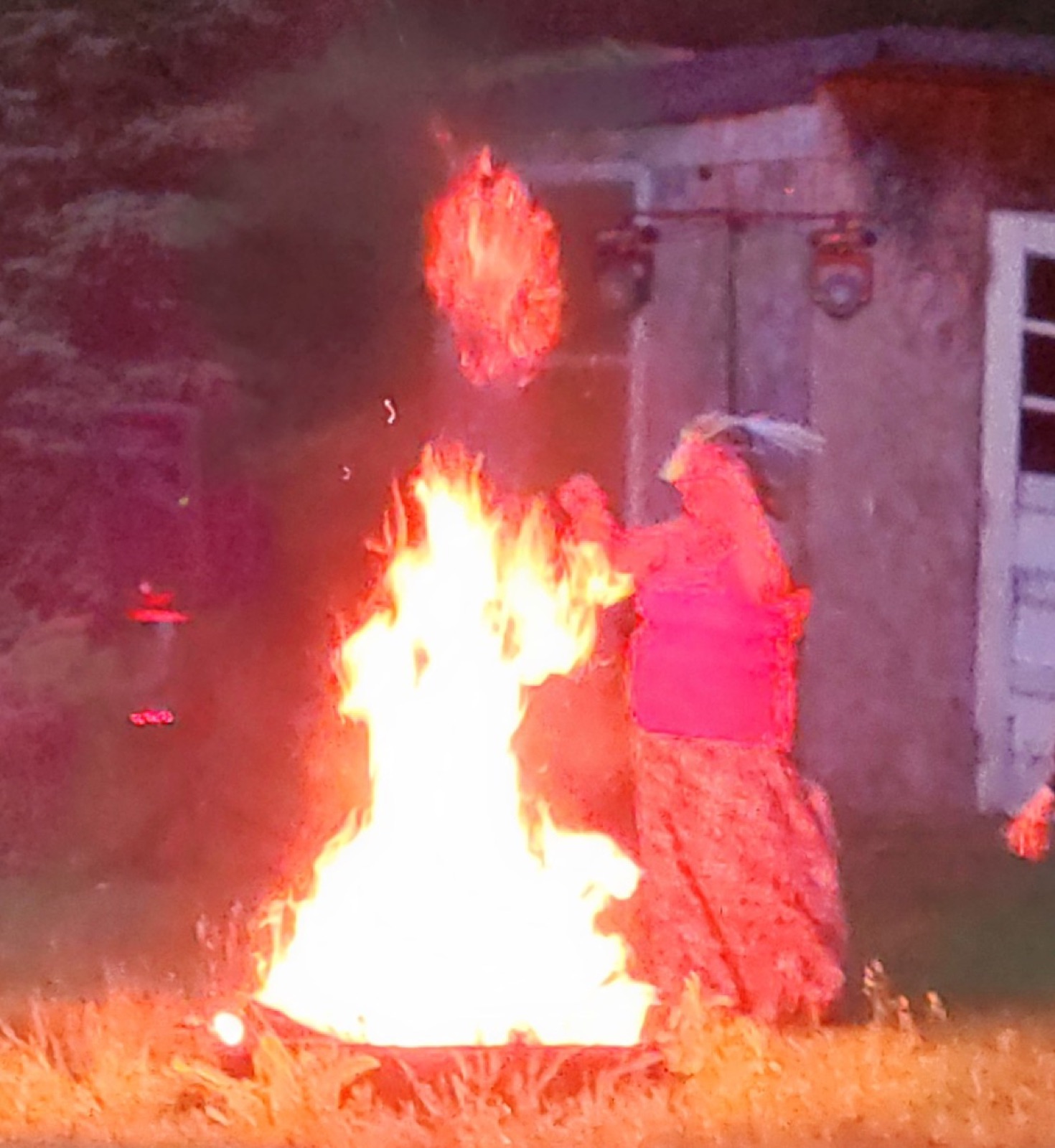 A fire burning beside a seated attendee at night